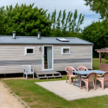 Moderne stacaravan met lichte gevel en een tuinset op een camping, omringd door groen en klaar voor een ontspannen vakantie